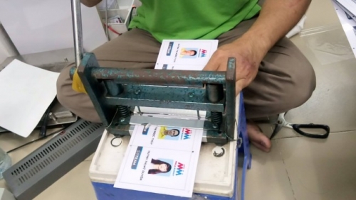 Nhân viên In Thẻ Nhựa đang tiến hành khâu gia công thẻ bảo hành, thẻ nhựa với máy bấm lỗ 4 góc thẻ trước khi đem đi dập viền thẻ